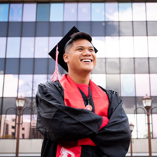 Graduate in a gown and cap, smiling.